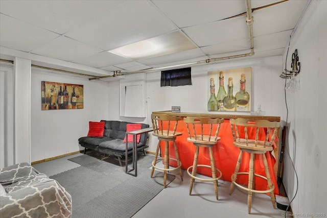 bar featuring baseboards, a dry bar, and a drop ceiling