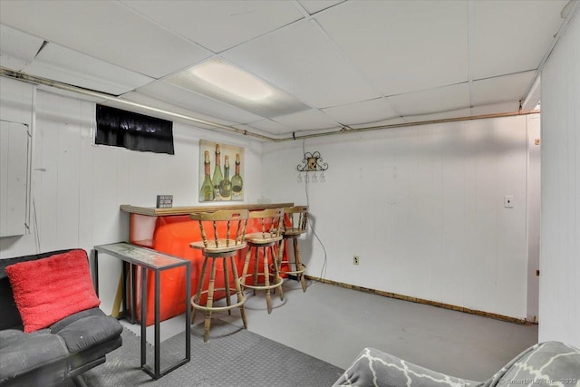 bar featuring baseboards, a drop ceiling, a dry bar, and finished concrete floors
