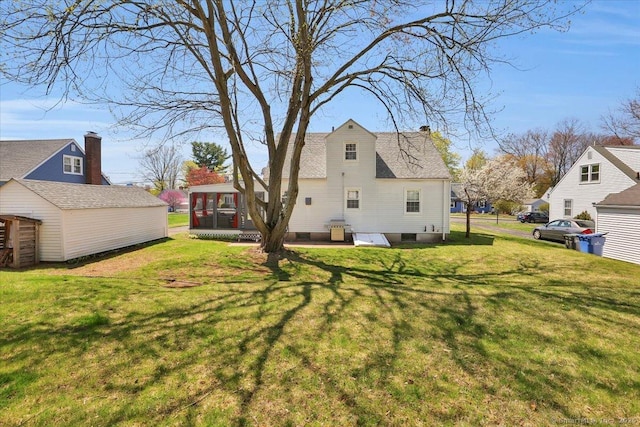 rear view of house featuring a yard, a chimney, and a sunroom