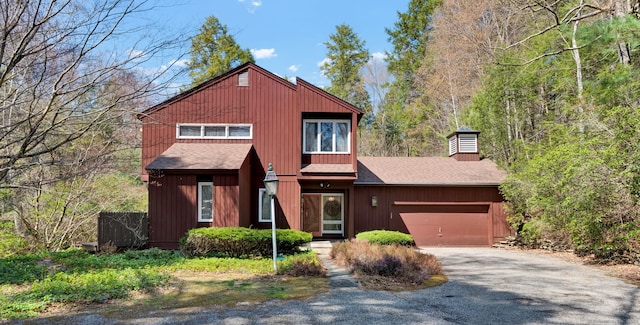 rustic home featuring a chimney, a garage, roof with shingles, and gravel driveway