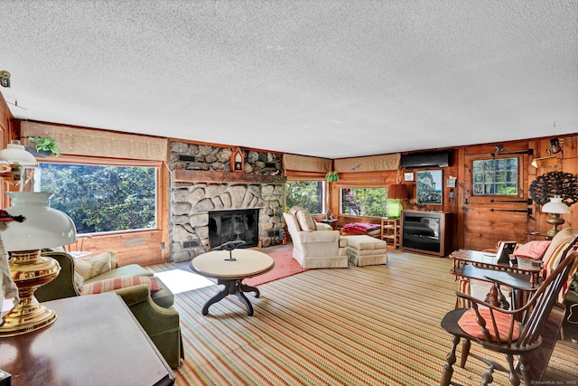 living area featuring a textured ceiling, wood walls, and a stone fireplace