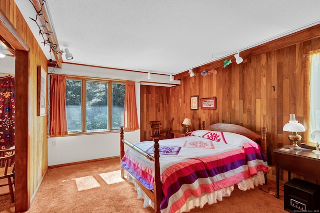 carpeted bedroom featuring rail lighting, wood walls, and baseboards