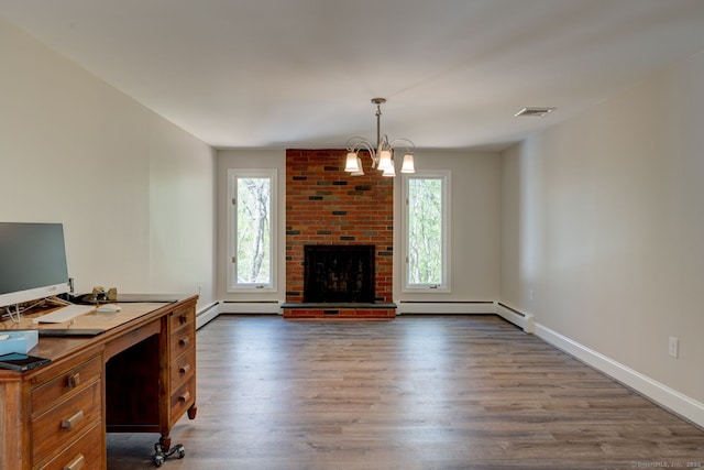 office area featuring wood finished floors, a baseboard heating unit, a healthy amount of sunlight, and visible vents
