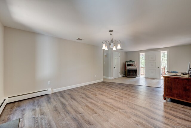 unfurnished living room featuring visible vents, baseboard heating, baseboards, light wood finished floors, and an inviting chandelier