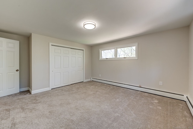 unfurnished bedroom with baseboards, carpet, a closet, and a baseboard heating unit