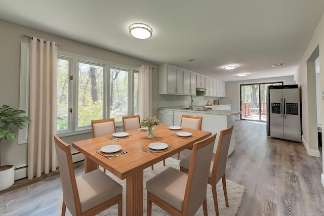 dining area with visible vents, a baseboard radiator, and light wood-type flooring