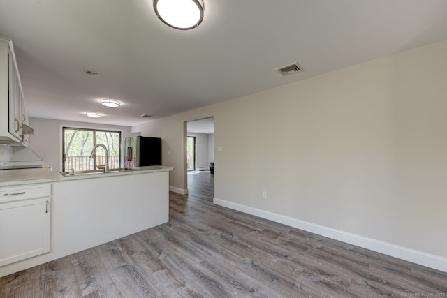 kitchen featuring visible vents, wood finished floors, high end fridge, open floor plan, and a sink