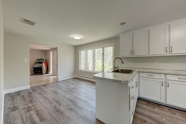 kitchen with white cabinets, visible vents, a sink, and light countertops