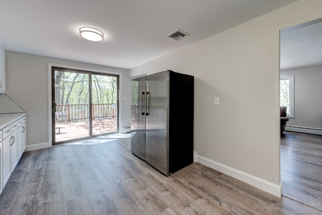 kitchen with a baseboard radiator, white cabinets, freestanding refrigerator, and light wood finished floors