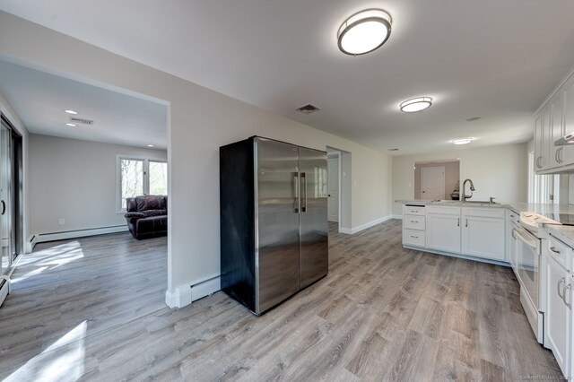 kitchen with visible vents, a peninsula, high end fridge, a baseboard radiator, and electric stove
