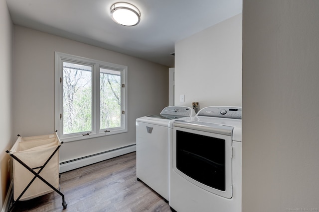 washroom with laundry area, separate washer and dryer, light wood-style flooring, and baseboard heating