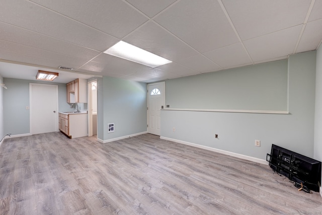 unfurnished living room with baseboards, visible vents, a sink, and light wood finished floors