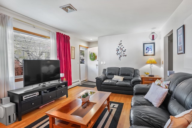 living area featuring a baseboard heating unit, visible vents, and light wood-style floors