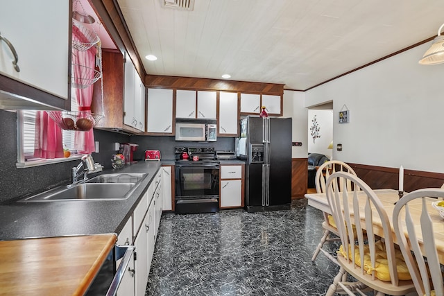 kitchen with a sink, white cabinetry, black appliances, and dark countertops