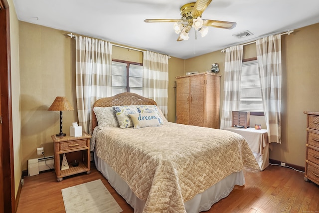 bedroom with ceiling fan, a baseboard radiator, wood finished floors, and visible vents