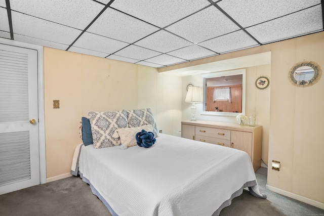 bedroom featuring carpet floors, baseboards, and a drop ceiling