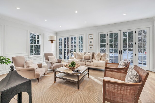 living room featuring recessed lighting, ornamental molding, french doors, and a decorative wall