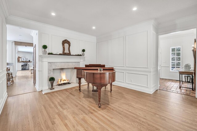 living area featuring ornamental molding, a decorative wall, and light wood-style flooring