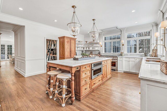 kitchen with appliances with stainless steel finishes, open shelves, light wood-type flooring, a sink, and a notable chandelier