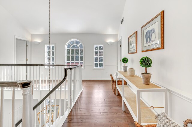 hallway featuring visible vents, baseboards, an upstairs landing, and hardwood / wood-style flooring