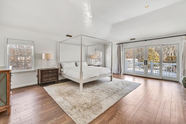 bedroom with visible vents, baseboards, wood-type flooring, lofted ceiling, and access to outside