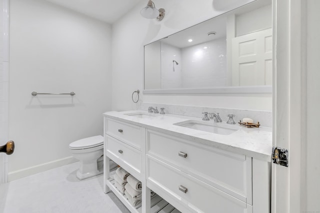bathroom featuring a sink, baseboards, toilet, and double vanity