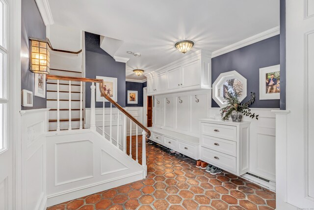 interior space with crown molding, a decorative wall, and a wainscoted wall