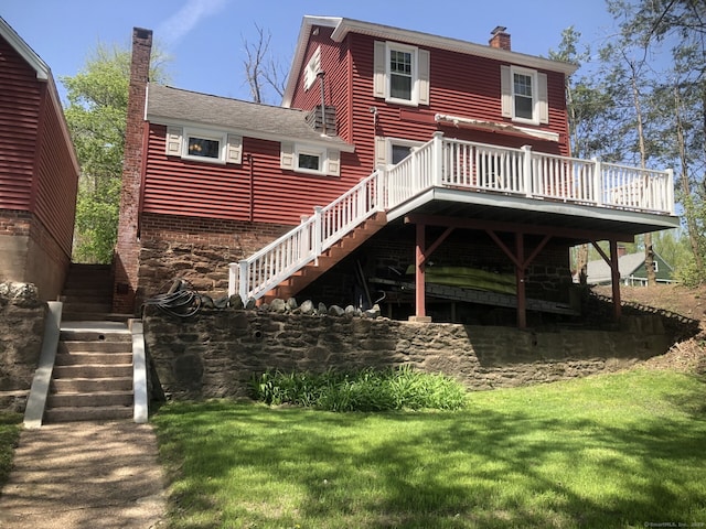 rear view of house with a chimney, a lawn, a wooden deck, and stairway