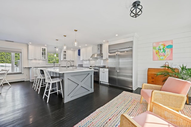 kitchen with glass insert cabinets, tasteful backsplash, wall chimney exhaust hood, and high quality appliances