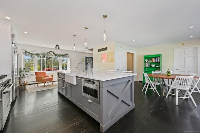kitchen featuring light countertops, a sink, dark wood finished floors, gray cabinetry, and stainless steel appliances