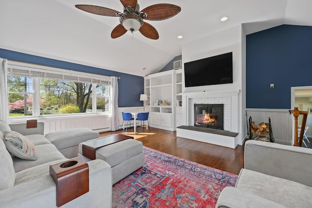 living area with wood finished floors, ceiling fan, lofted ceiling, and a wainscoted wall