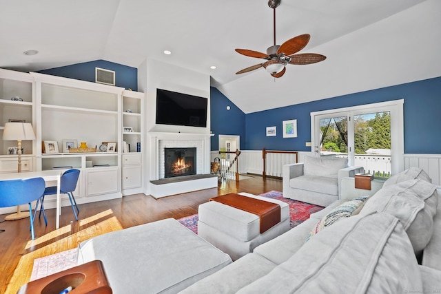 living area featuring visible vents, wainscoting, lofted ceiling, and wood finished floors