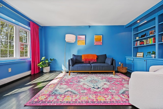 living room featuring built in features, wood finished floors, baseboards, a baseboard radiator, and ornamental molding