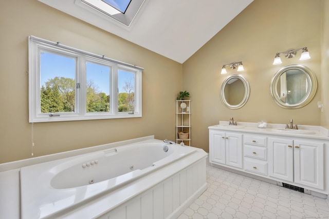 full bathroom with double vanity, a sink, lofted ceiling with skylight, and a jetted tub