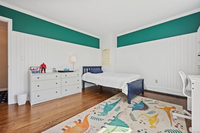 bedroom featuring crown molding, baseboard heating, and wood finished floors