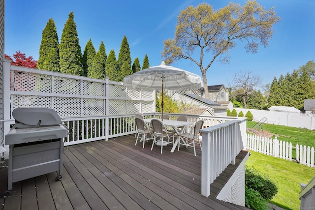 wooden terrace with fence, outdoor dining space, a yard, and grilling area