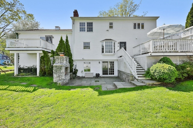 rear view of property featuring a wooden deck, stairway, a chimney, a patio area, and a lawn
