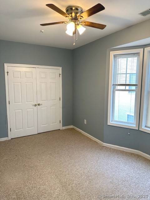 unfurnished bedroom with baseboards, light carpet, and visible vents