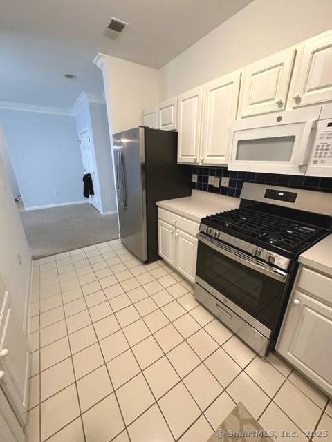 kitchen featuring visible vents, crown molding, appliances with stainless steel finishes, and white cabinets