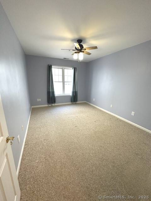 empty room with baseboards, a ceiling fan, and carpet