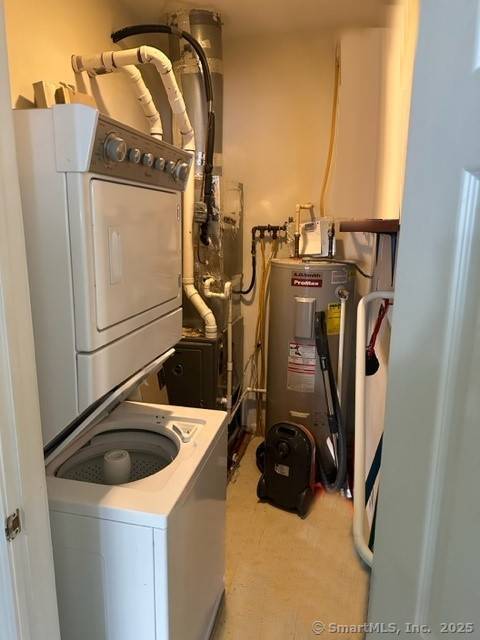 utility room with stacked washer / drying machine and water heater