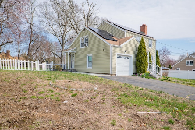50 Fox Hill Rd, Stratford, CT 06614 - view of property exterior with fence, an attached garage, aphalt driveway, roof mounted solar panels, and a chimney