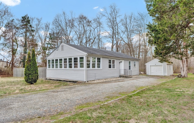 view of front of house with an outdoor structure, a front lawn, fence, driveway, and a detached garage