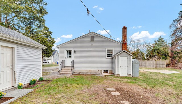 back of property with a lawn, a storage shed, fence, an outdoor structure, and entry steps