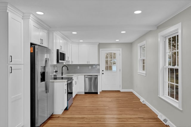 kitchen featuring visible vents, appliances with stainless steel finishes, light countertops, baseboards, and light wood-style floors