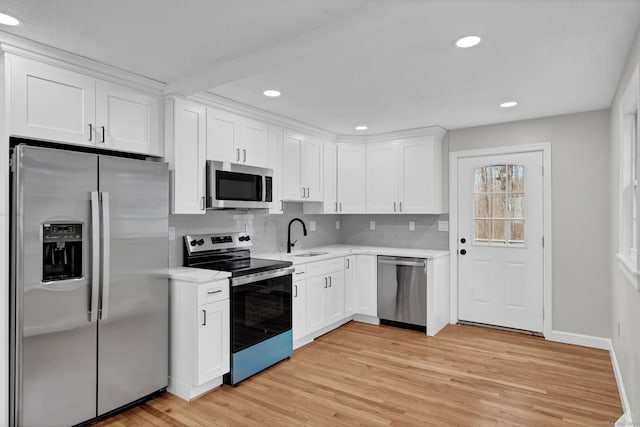 kitchen with light wood-style floors, light countertops, white cabinets, and stainless steel appliances