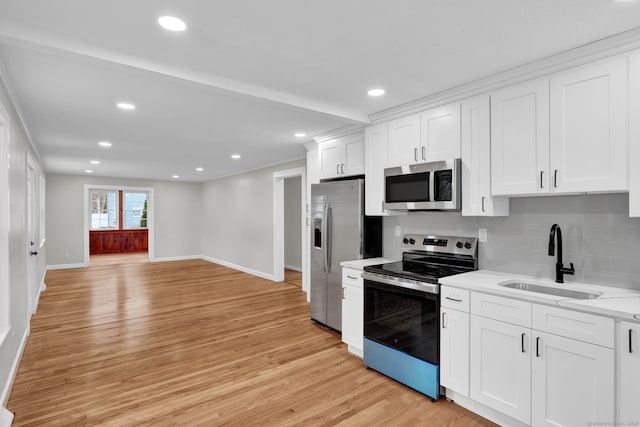 kitchen with appliances with stainless steel finishes, a sink, light wood-style flooring, baseboards, and backsplash