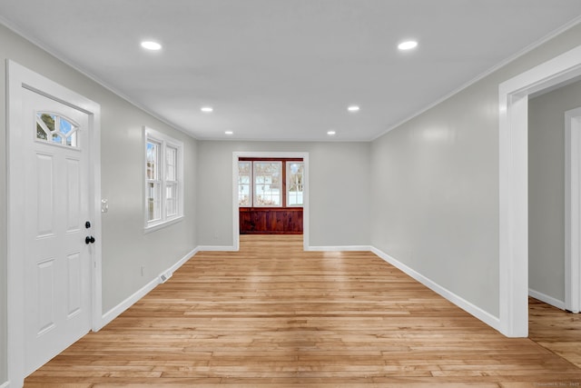 foyer entrance with crown molding, baseboards, and light wood-type flooring