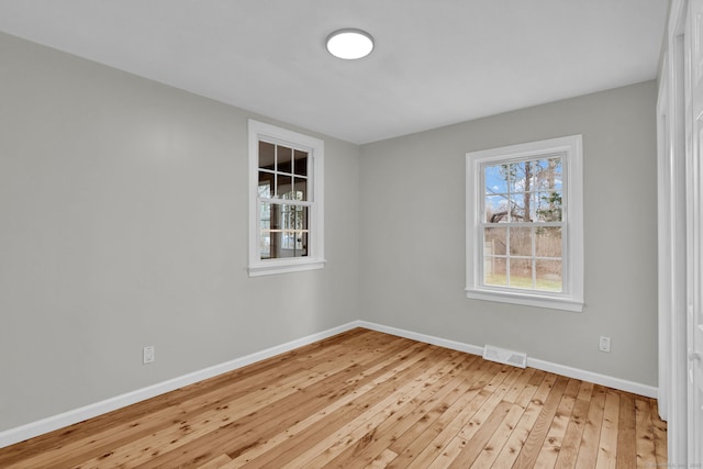 unfurnished room featuring baseboards, visible vents, and hardwood / wood-style floors