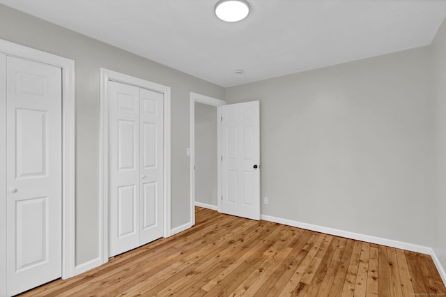 unfurnished bedroom featuring baseboards, light wood-style floors, and a closet